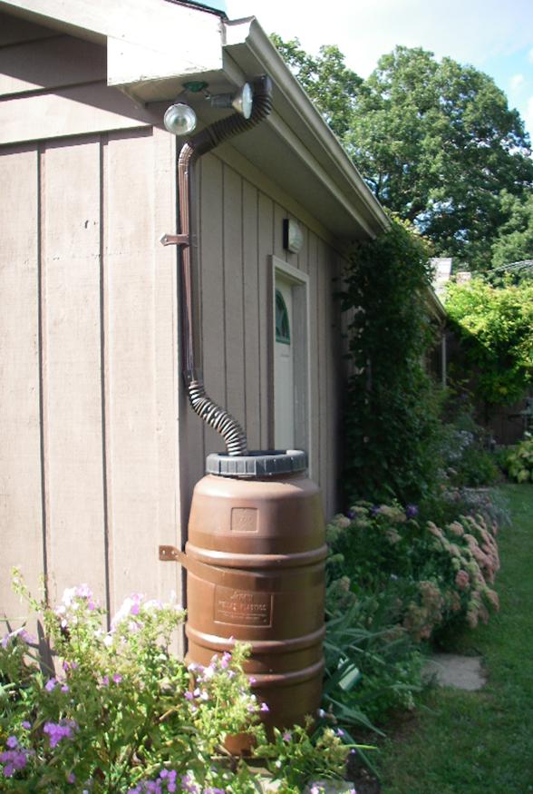 Brown Rain Barrel in Garden Area Attached to Roof Drainage